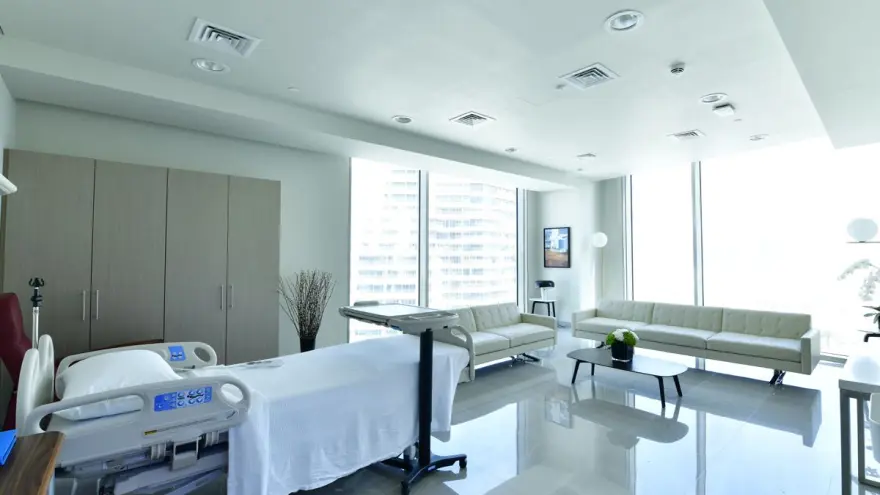 A hospital room with white furniture and windows.